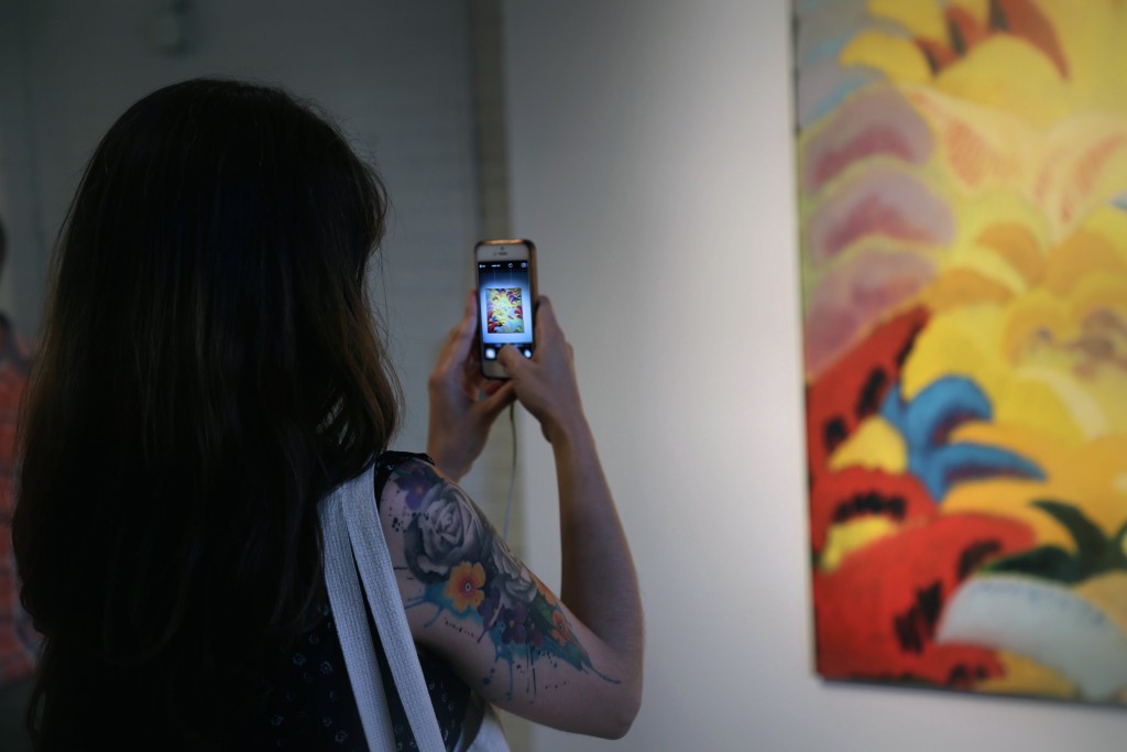 Adrienne Jimenez getting a pic of a painting by Alan Prazniak at PROTO Gallery